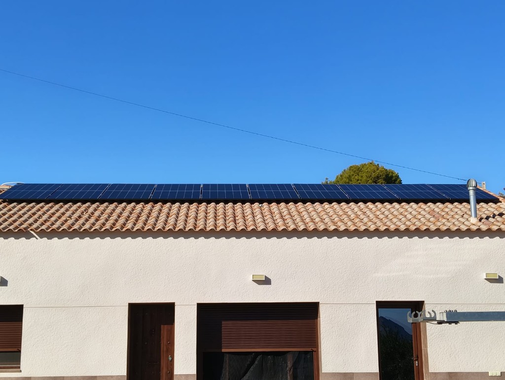 Fila de paneles solares monocristalinos en cubierta residencial bajo cielo despejado